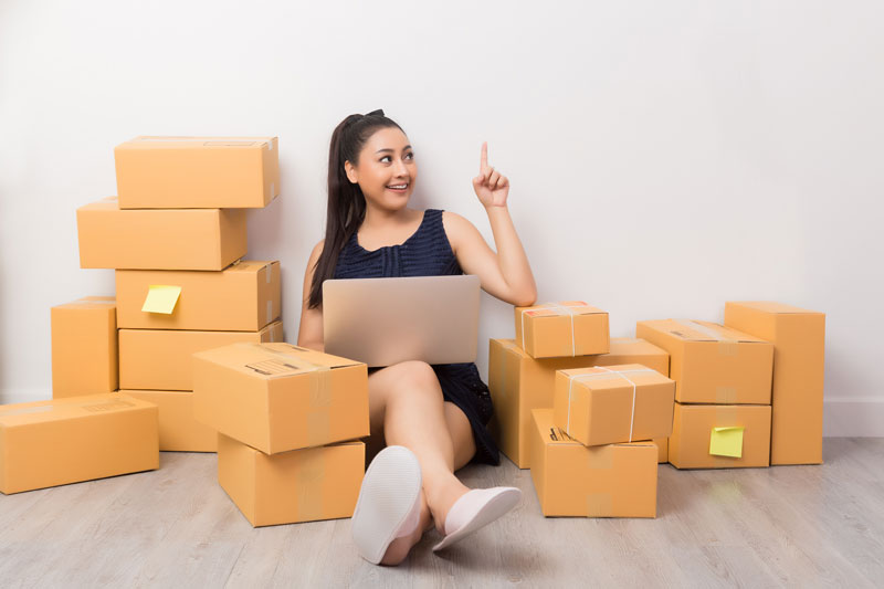 foto di una donna seduta con pc sulle gambe circondata da scatole e indica il servizio di top delivery